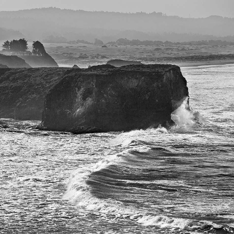 Surf crashes against the bluff while the wave continues on into the gulch