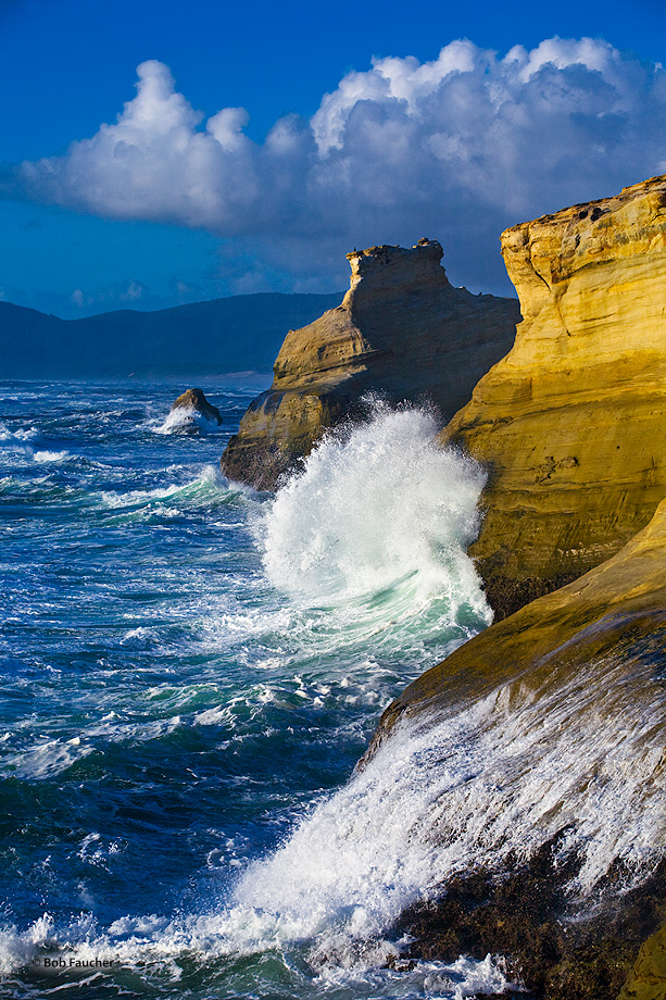 An incoming wave attacks one wall of Cape Kiwanda while a spent wave retreats down the face of an adjacent wall