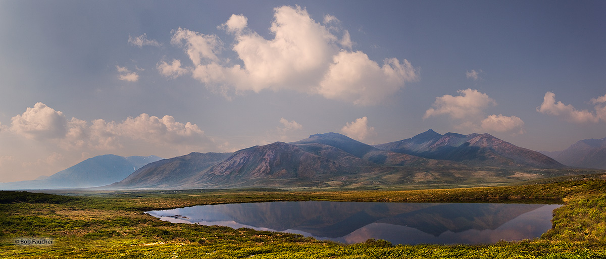 Reflected on the surface of a tarn in the tundra, the Blackstone Range is a part of the Ogilvie Mountains