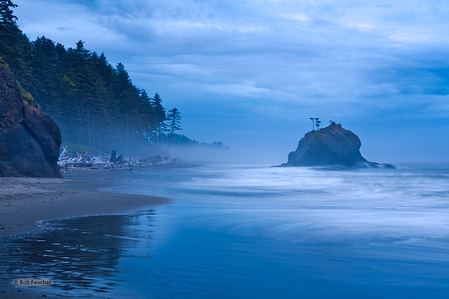 Under low clouds, an isolated sea stack that is surrounded by whitewater which has been exaggerated by a long exposure is lit...