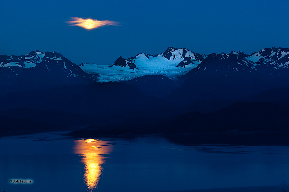Blue Moon, the second full moon in August, 2015, rises over Dixon Glacier in the Kenai Range, with its reflection streaking across...