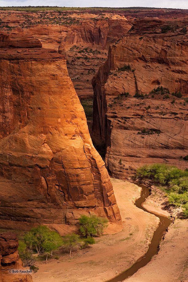 Late afternoon sun breaks through the clouds to light the rock face and river as it winds through a narrow slot in Canyon de...