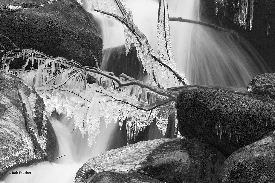 Icicles form on rocks and tree limbs over a flowing creek