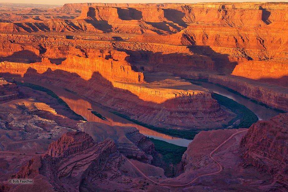 Morning sun highlights the White Rim and reflects off the gooseneck onto the Colorado River
