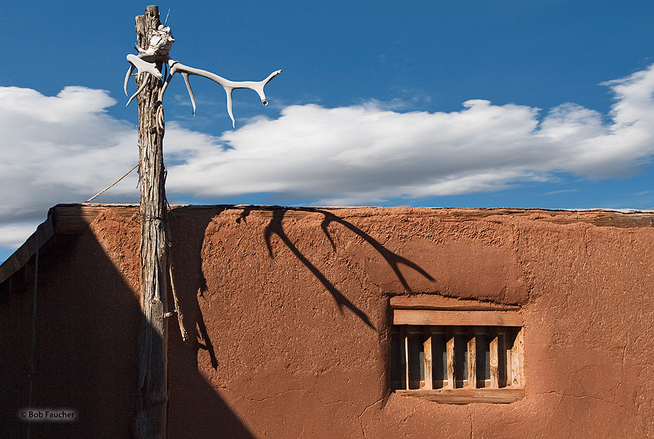 Shadow from mounted elk antlers encroach on an exterior window at El Rancho de Las Golondrios, a living history museum