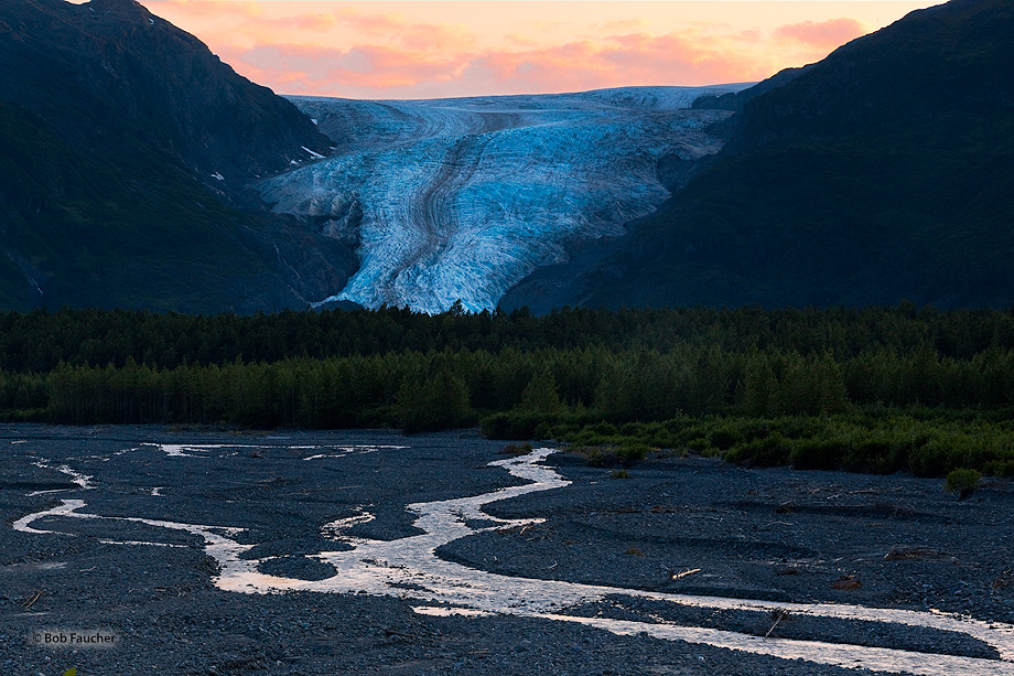 Light clouds and the Resurrection River reflect warm sunset colors above Exit Glacier