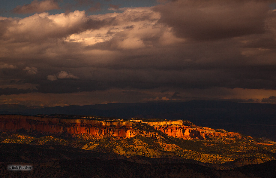 Sunset light breaks through an opening in the clouds highlighting the twin mesas at the southwest end of Bryce Amphitheater