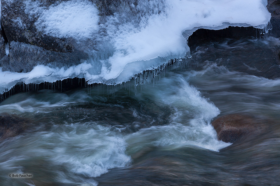 Ice and snow shelves form on the sides of rocks along the river. These, in turn, form icicles from snow melt and water splashed...