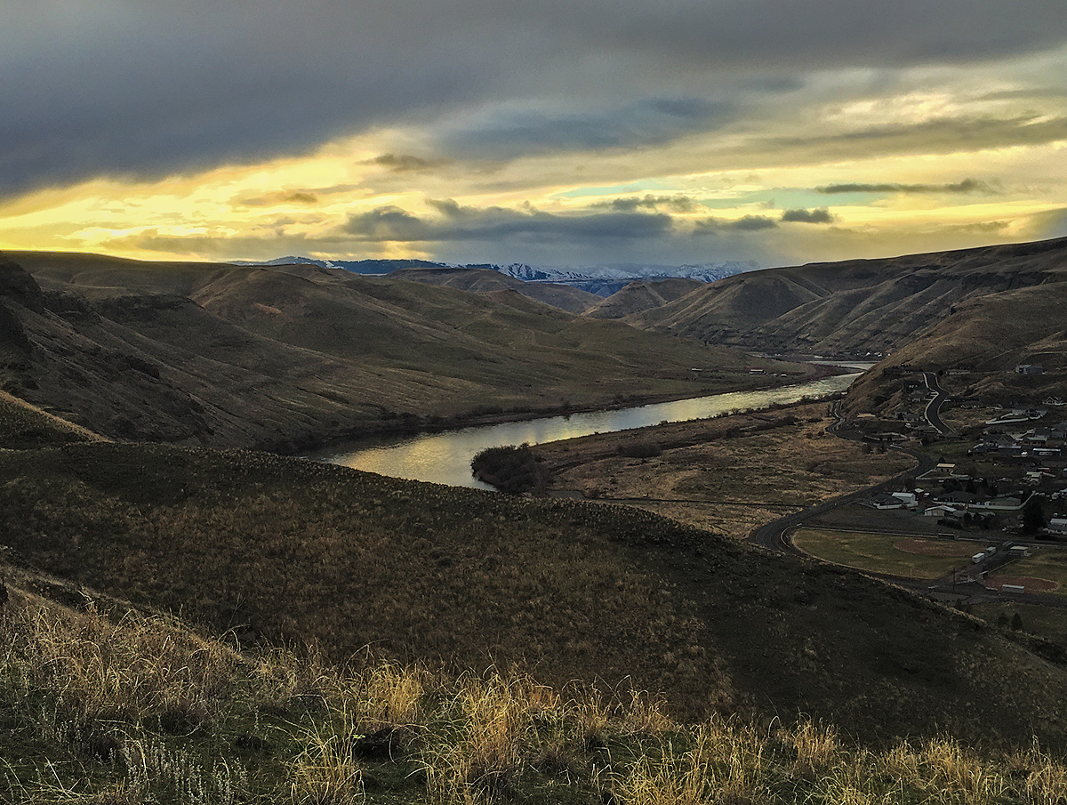 As viewed from atop Devil's Slide Trail, morning sunlight breaks under the clouds over the foothills in Lewiston, Idaho, casting...