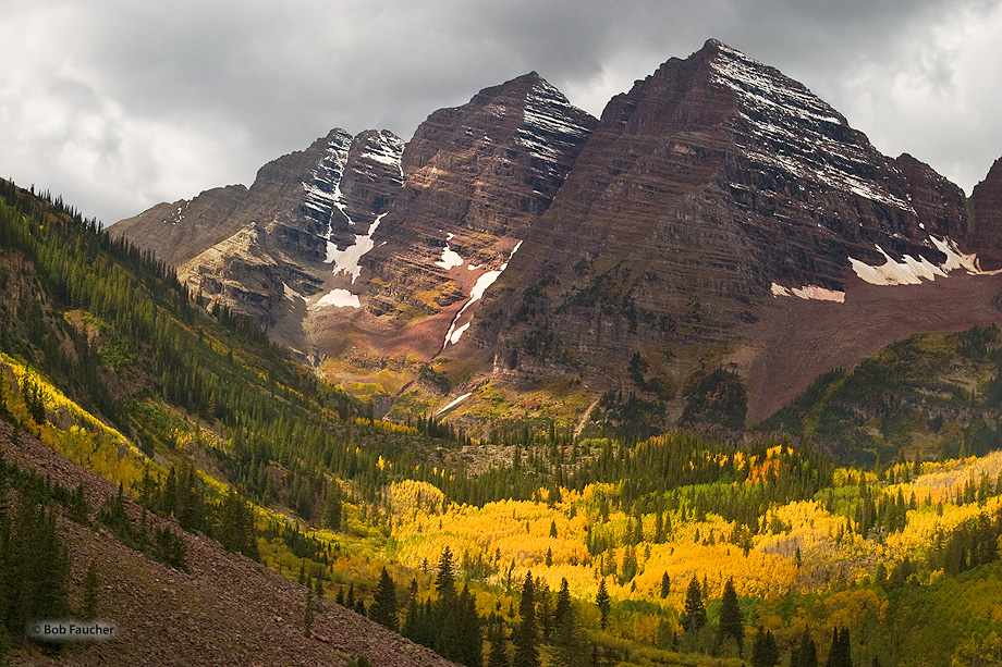 Storm clouds hang ominously over the peaks of the Maroon Bells. Yet a beam of sumlight manages to penetrate through the clouds...
