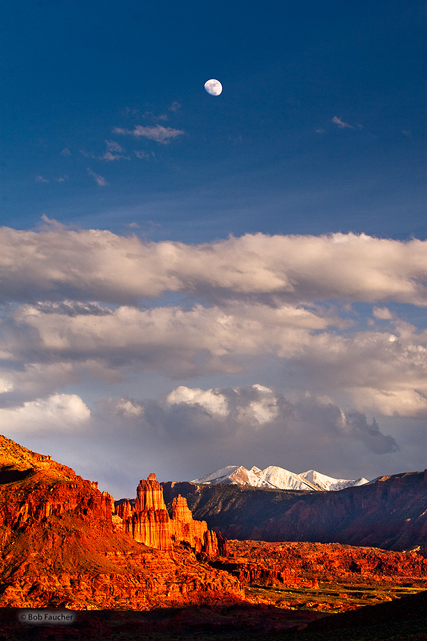 With the moon rising high above, Fisher Towers glow their signature deep red with strong sidelight in the afternoon.
