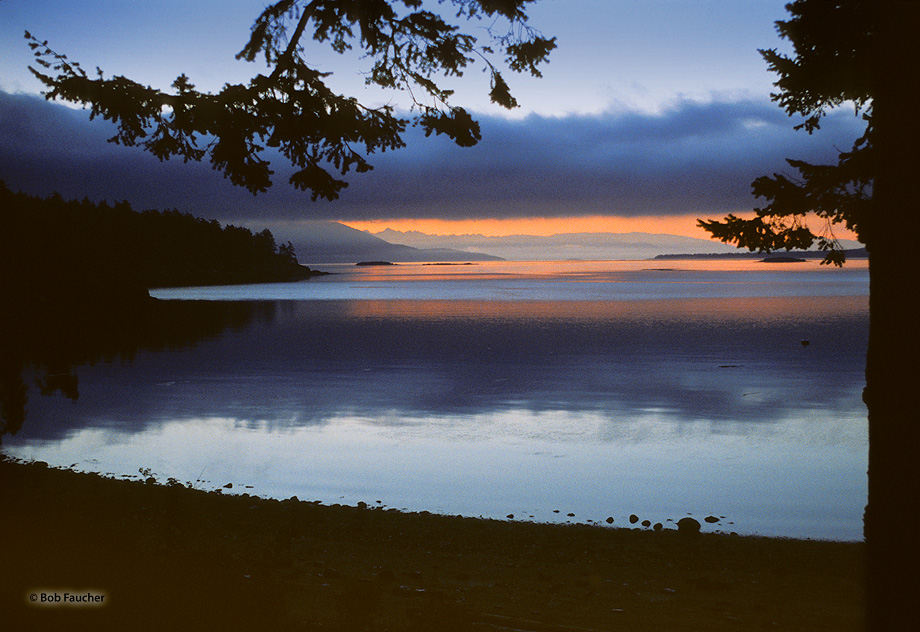 Morning twilight view of the Cascade Range shrouded in orange in the background, across Obstruction Pass from near the town of...