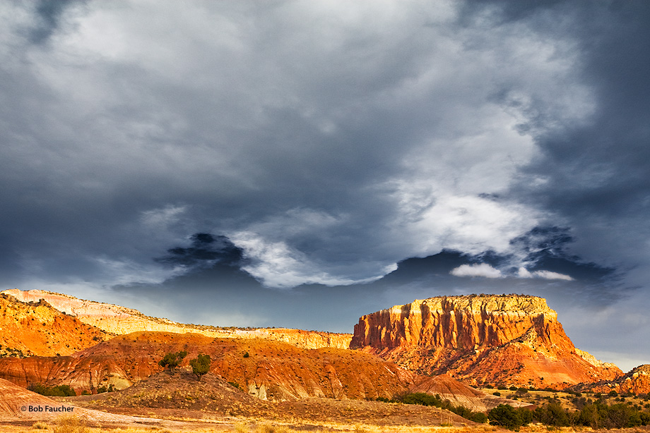 Dark, gloomy clouds move past Orphan Mesa while a break in the clouds at the horizon allows afternoon light to illuminate the...