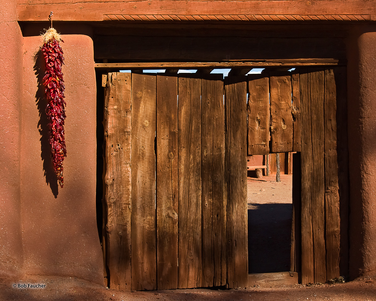 Ristras flank the main gate, with a pedestrian doorway (zaguan), into the walled central plaza of El Rancho de las Golondrinas...