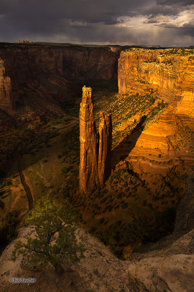 Strong sun breaks through a layer of clouds, races up Monument Canyon in Canyon de Chelly to illuminate its best known feature...