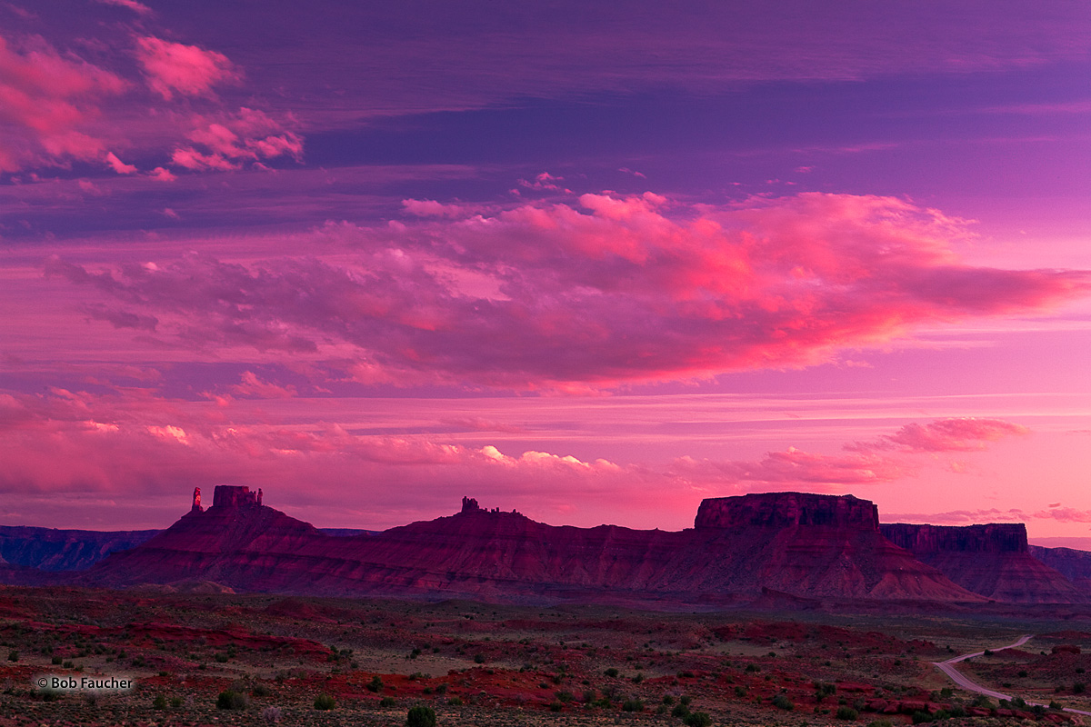 A brilliant sunset, with an intense magenta hue, bathes the sky, clouds and rocky formations bordering the Richardson Amphitheater...