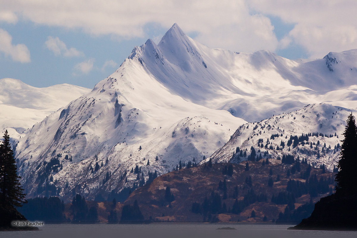 With a sky filled with cluods, Elbow Mountain rises above Sharatin Bay, a finger of the larger Kizhuyak Bay.