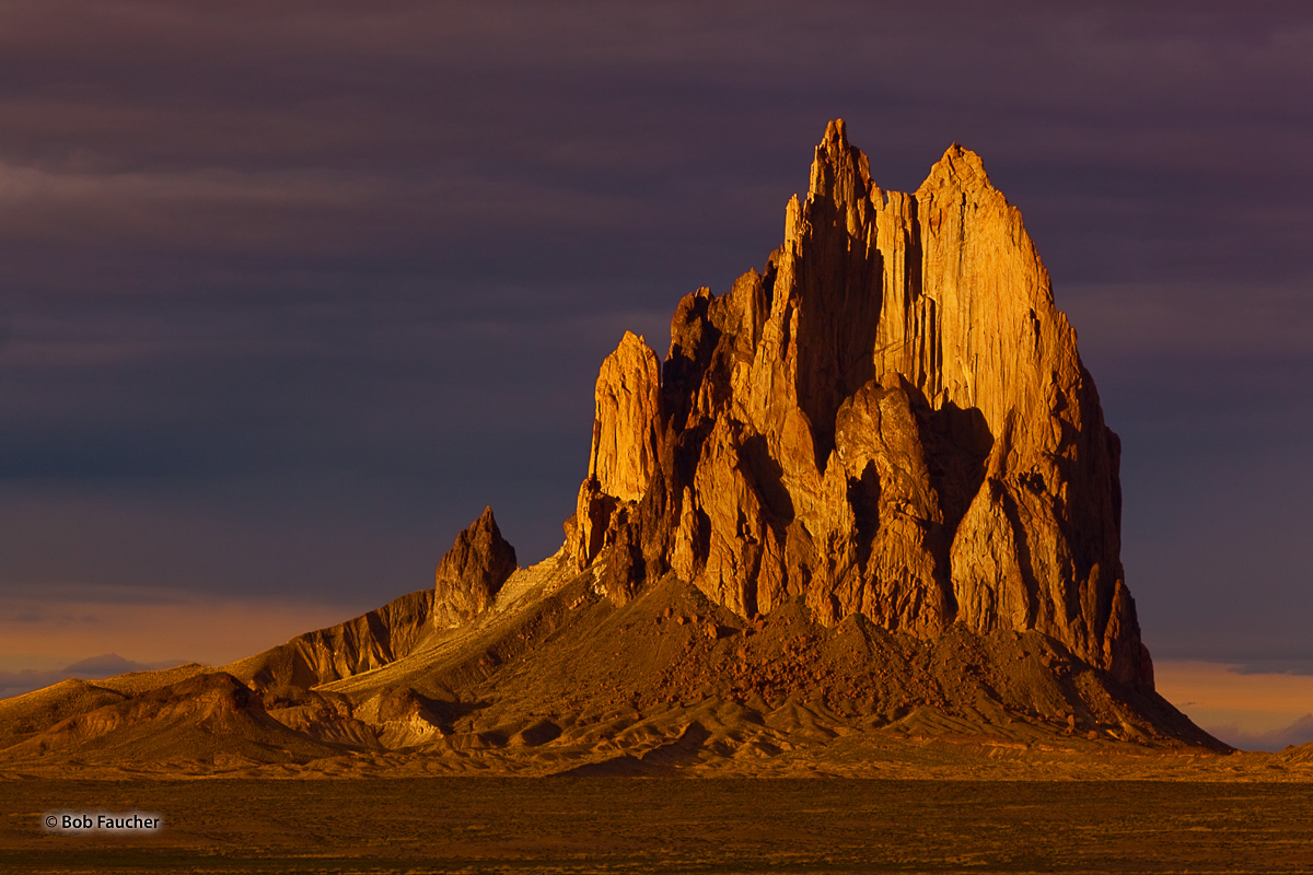 Shiprock, a diatremic monadnock, rises abruptly from the virtually level surrounding plain. The west face glows with evening...