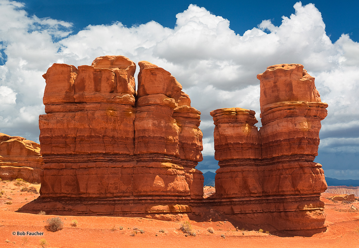 Two groups of hoodoos near Burro Wash along the Notom–Bullfrog Road frame a cloud-shrouded peak of the Henry Mountains in the...