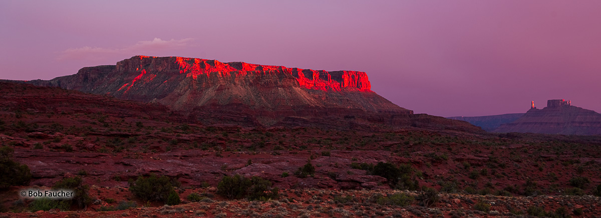 Fisher Mesa, bathed in intense alpenglow, as are the Priest and Nuns formation atop Castle Rock in the background, commands the...