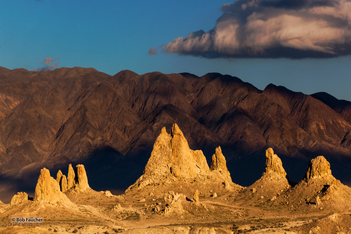 Late evening light plays on some tufa spires, making them glow against the backdrop of brown hills in the Trona Pinnacles, a...