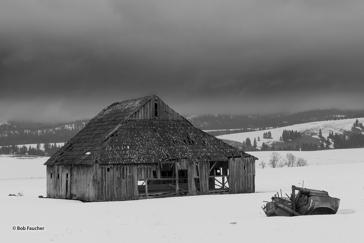 An old barn and farming implement remain stuck in the pristine snow