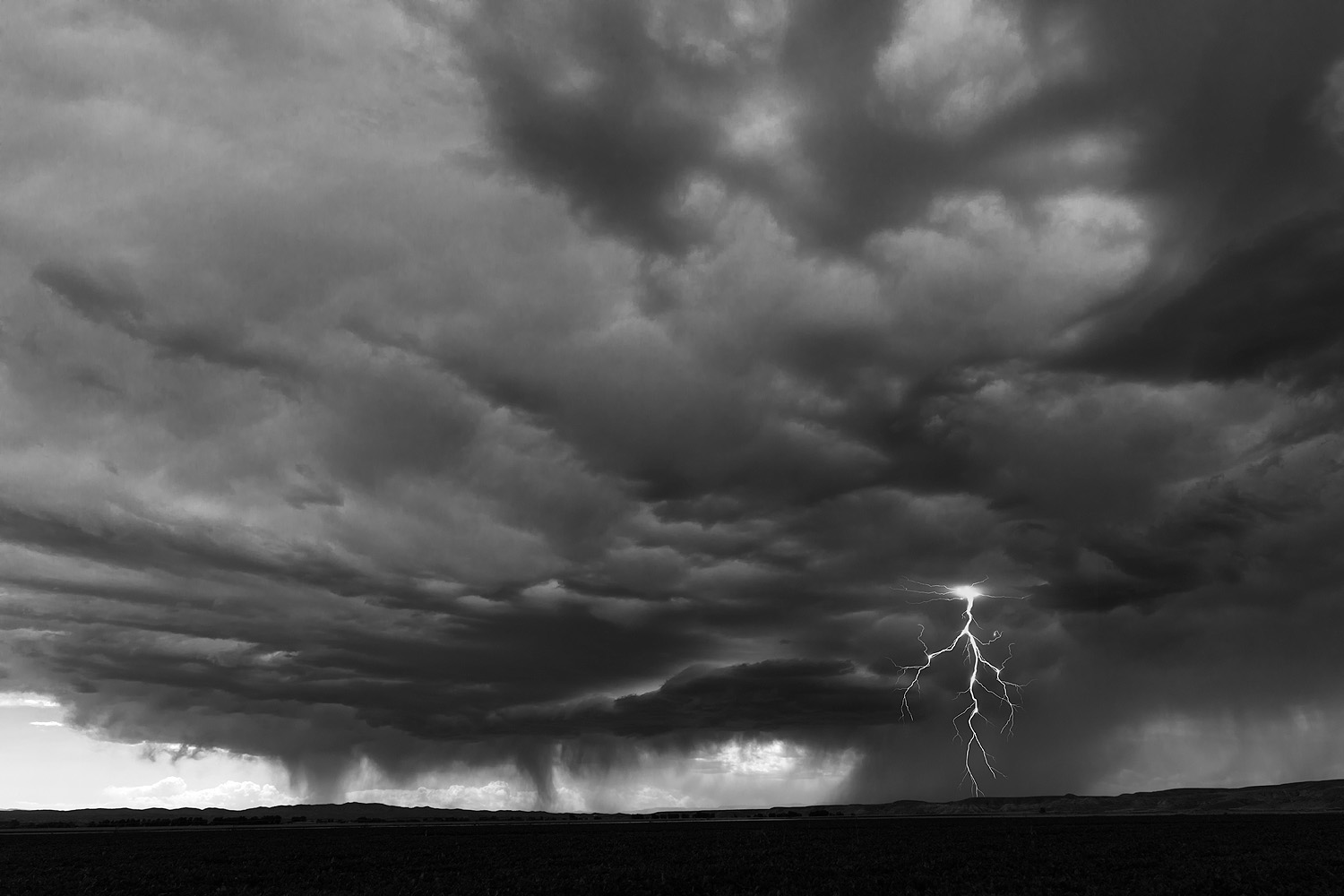 A midday electrical storm passes over a field along Lane 14, near Thermopolis, Wyoming