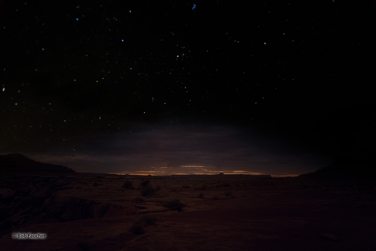 Early dawn begins to peek over the horizon, with the sky still very dark in Canyonlands NP along the White Rim Trail in the Island...
