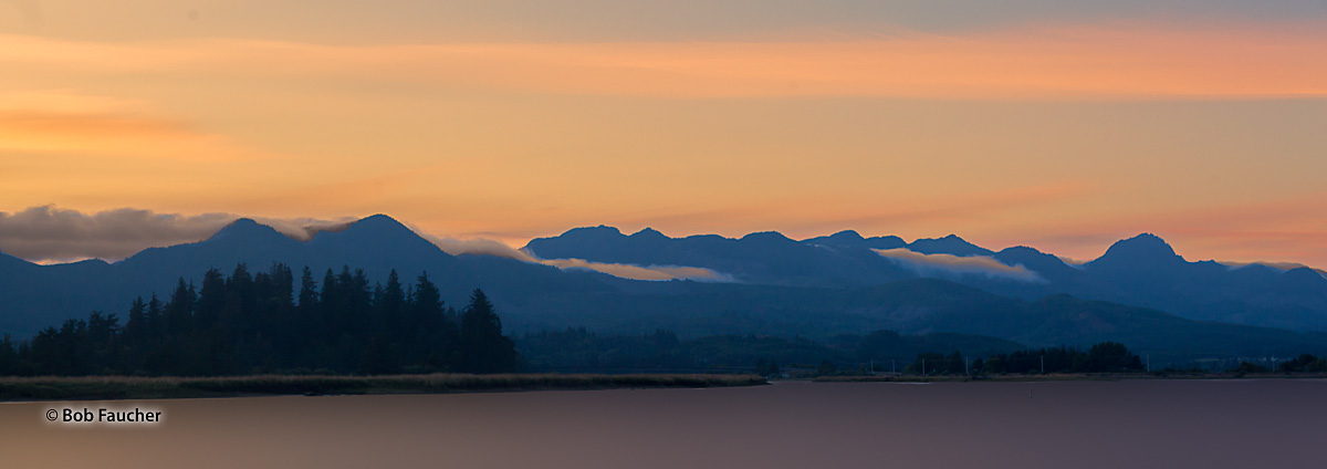 Sunset colors saturate the clouds and fog, rolling in from the Pacific coast, as they flow over the Northern Oregon Coast Range...