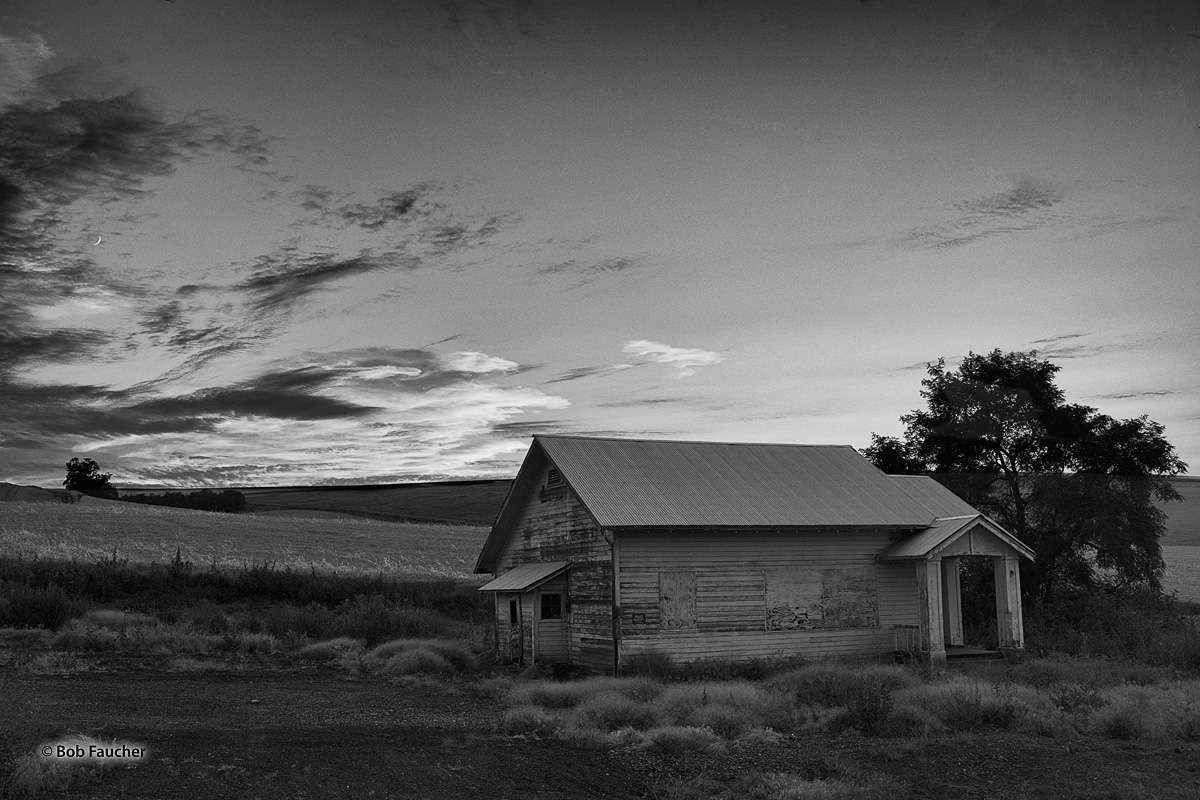 A unused dwelling rests at the end of another day, punctuated by blazing clouds near the horizon at twilight.