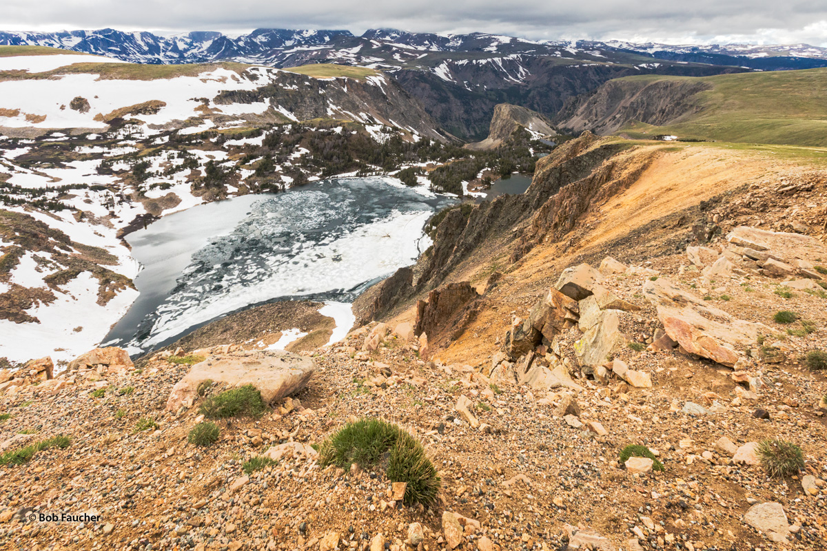 Two mesmerizing bodies of water, covered with snow and ice and separated by a narrow land bridge, are seen below beautiful Beartooth...