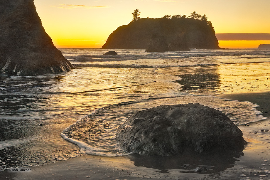 A round rock near the edge of the surf line reflects itself in the wet sand behind it, but also the water that had crashed upon...