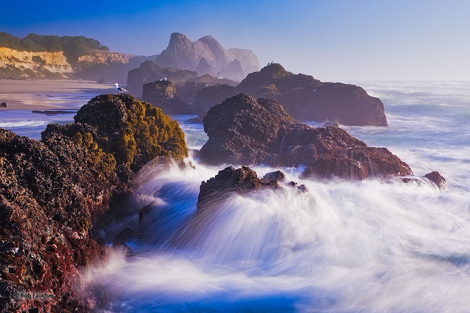 A long exposure creates long streaks of the splashing water as heavy surf crashes on the exposed rocks at Seal Rocks