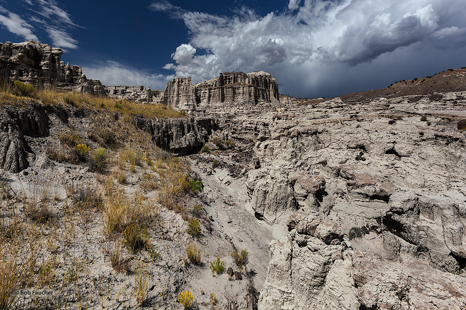 Valley of a dry river leads to Plaza Blanca's most prominent formation, under marvelous Monsoon clouds
